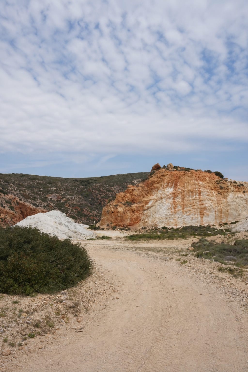 Unpaved road leading through the rural landscape of Milos.